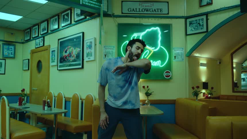 A man acts like hes licking his own arm while standing in a restaurant