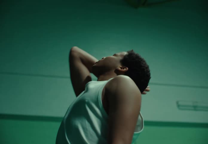 A black teenage boy dances in a darkened gym
