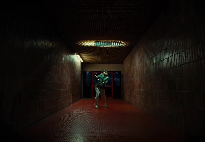 An asian person moves in a creepy way in a building hallway