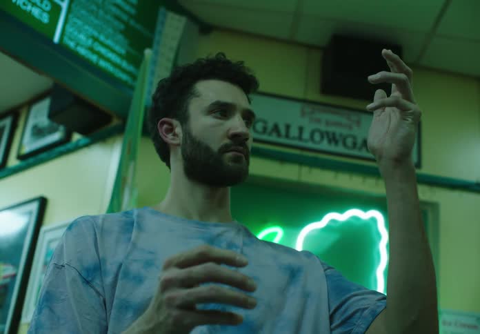 A young man in a blue shirt looks at his twitching hand