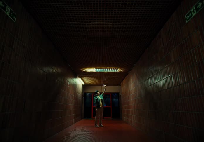 A woman standing in a hallway with red tiles and she has one arm raised up
