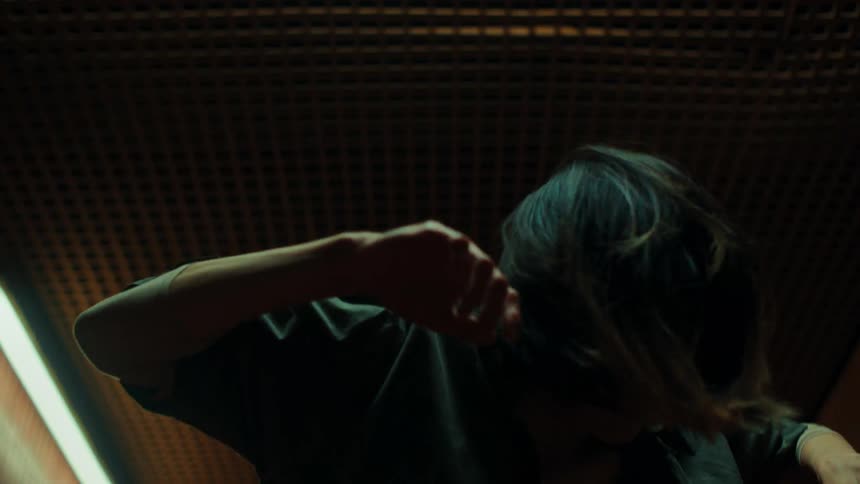 Woman dancing indoors with her arms shaking her hair being thrown back