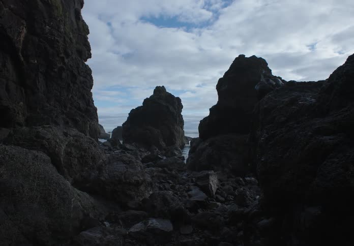 A view of the ocean through a gap between two rocky cliffs