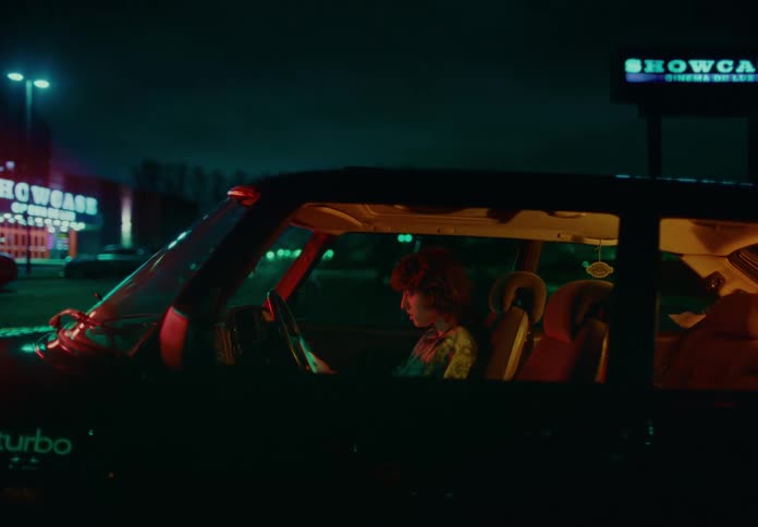 Person sitting in the passenger seat of a car parked in a place at night