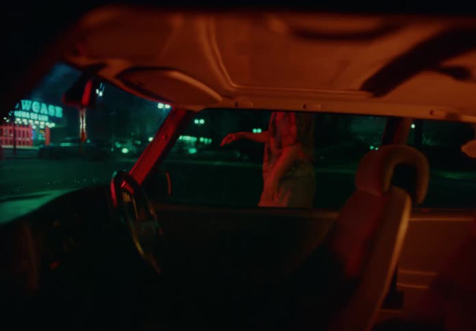 A person comes out of a car dancing at night