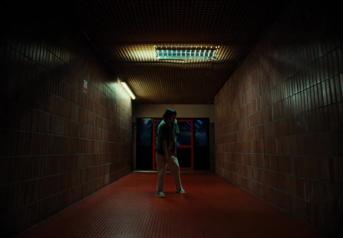 A woman dances alone in a dimly lit hallway at night