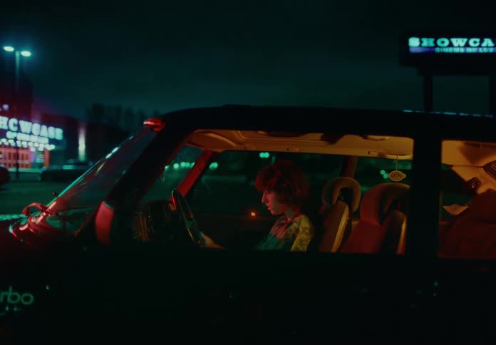 A woman sits in a car looking at a smartphone