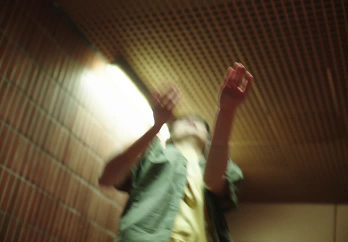 Female dancer with a green shirt and yellow t shirt dances in a room at night