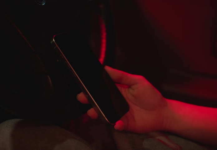 A person holds and taps a smartphone while sitting in a car