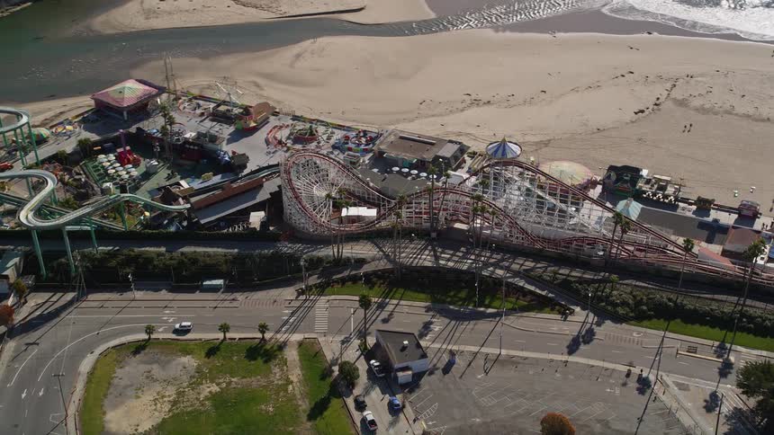 The brightly colored roller coaster twists and turns through a vibrant amusement park near the beach