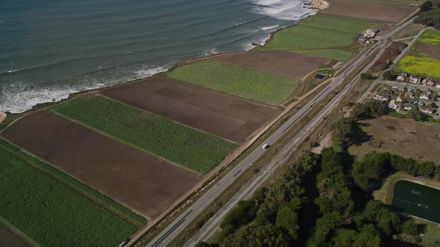 Aerial view of agricultural fields by the sea and with residential neighborhoods next door