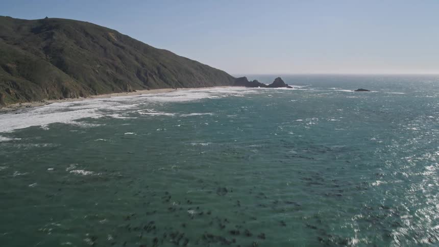 A coastline with a sandy beach and green hills