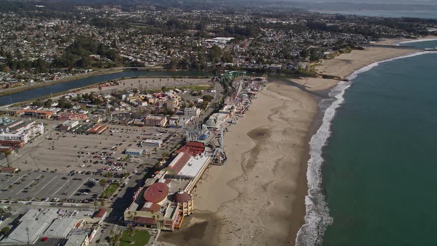 River flows into the ocean between a residential neighborhood and beach side stores