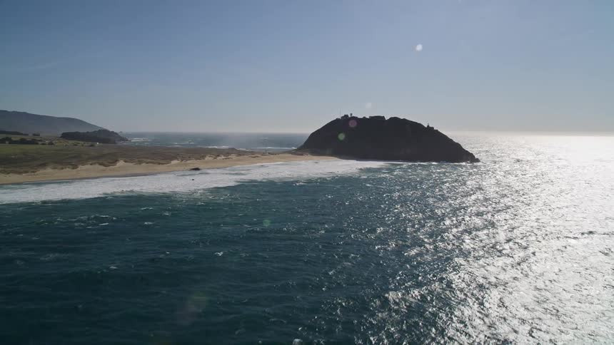 Aerial view of a beach peninsula ending on a rock formation