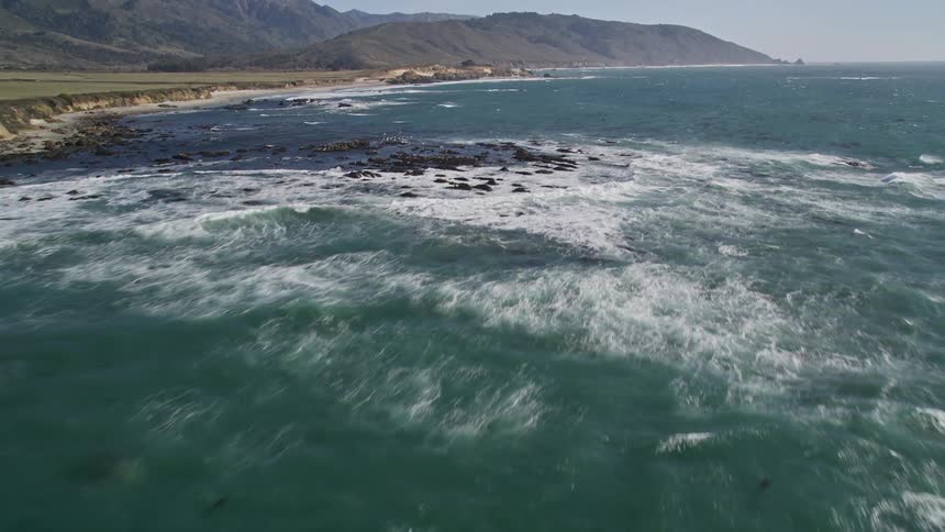 Landscape seen from above of an ocean with waves foamed with algae and at the edge of the coast