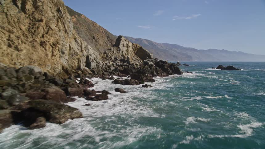 Aerial view of a rugged coastline with waves crashing against rocky cliffs
