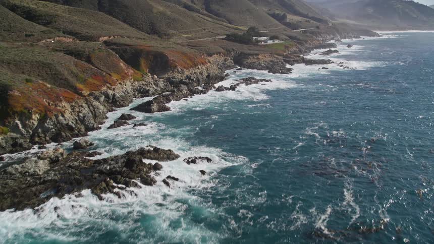 Ocean landscape with waves crashing on rocky shores by mountains on a peninsula