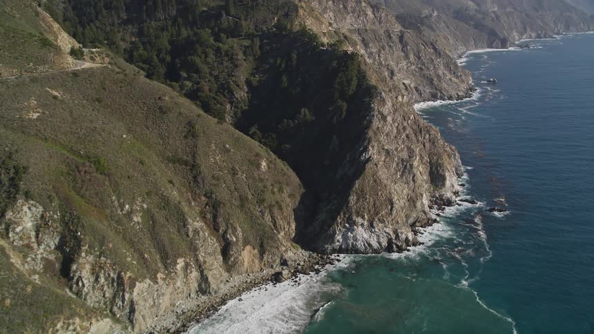Peninsula seen from above with waves hitting the mountainous coast with cliffs