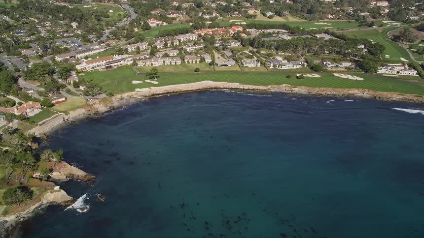 Aerial panorama of a blue lake surrounded by wooded coastline and residential neighborhoods
