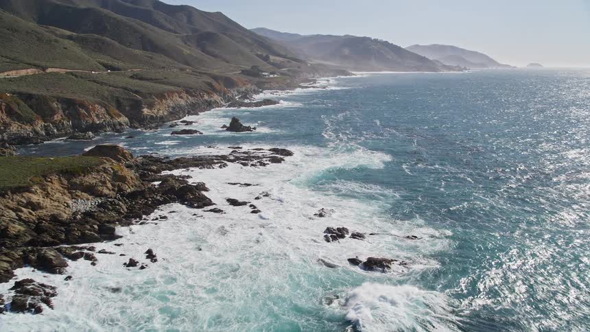 Ocean with seaweed and waves crashing on the rocky shore