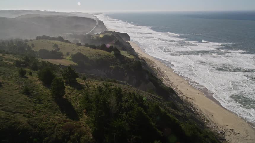 Aerial panorama of a beach on the edge of green mountains
