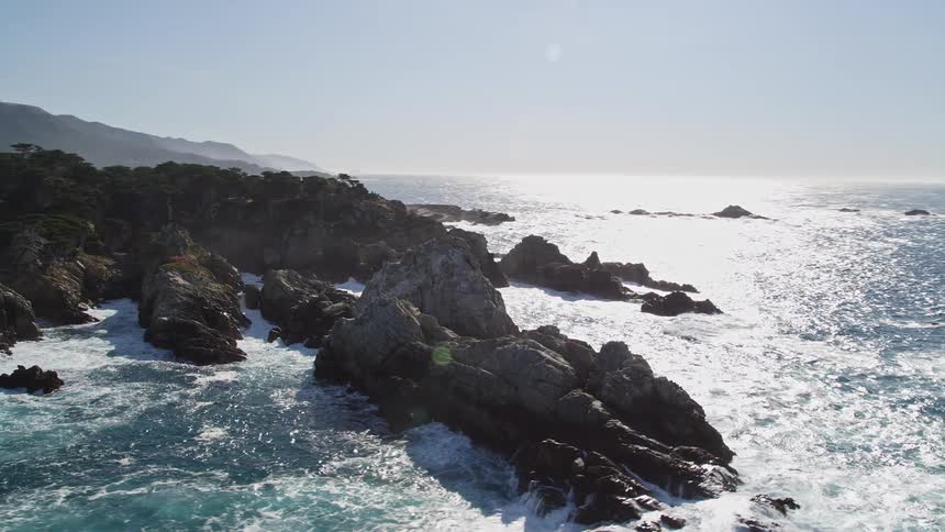 The aerial view captures the dramatic contrast between the rugged mosscovered cliffs and the turquoise water of a secluded beach