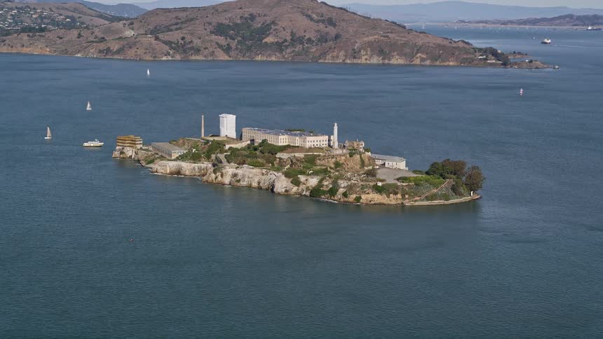The iconic rock of alcatraz island sits in the middle of a calm bay