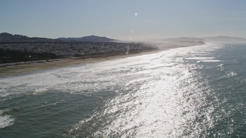Solar reflection on the vast ocean that bathes a beach with an urban city