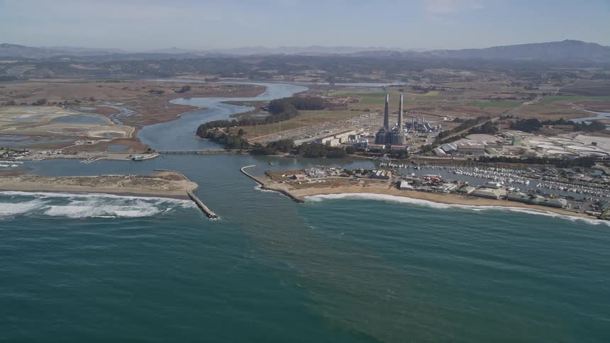 Building with dual chimneys towers over marina near river mouth