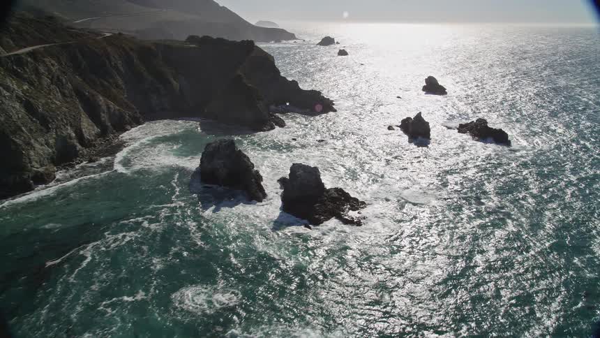 Aerial landscape of the suns reflection in an extensive sea that bathes the rocky and mountainous coast