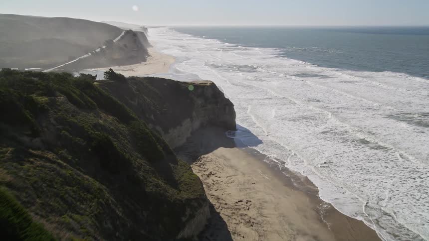 Aerial view reveals the majestic coastline with cliffs where the sea meets a beach