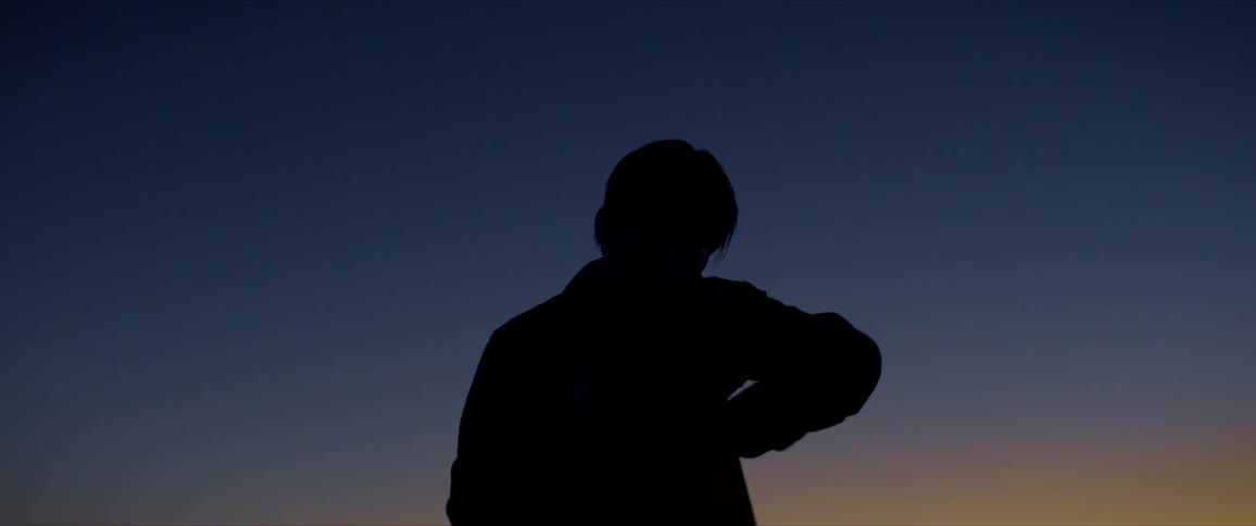Silhouette of a person dancing against a blue and yellow sky