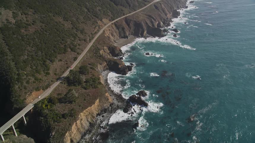 Aerial landscape of a long road winding through the mountains by the sea