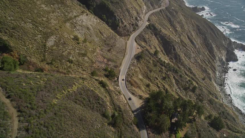 Aerial panorama of an extensive highway with cars through the mountains and the seaside