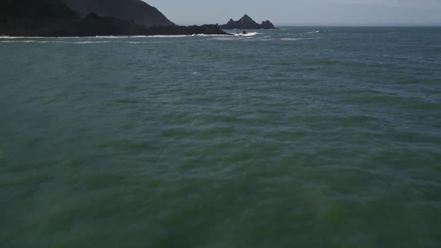 Panorama of a calm sea at the edge of the rocky coast during the clear blue sky day