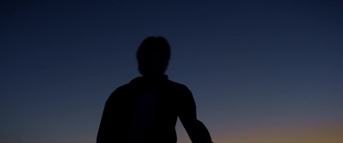 Silhouette of a man dancing against a blue sky
