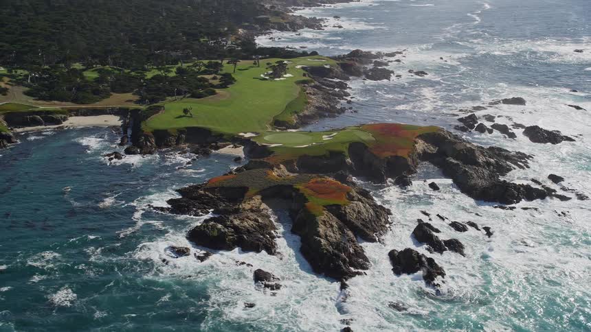 Sun glares offocean water near coastal golf course bordering forest