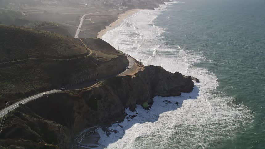 Mountains with a winding road with vehicle traffic and the seaside