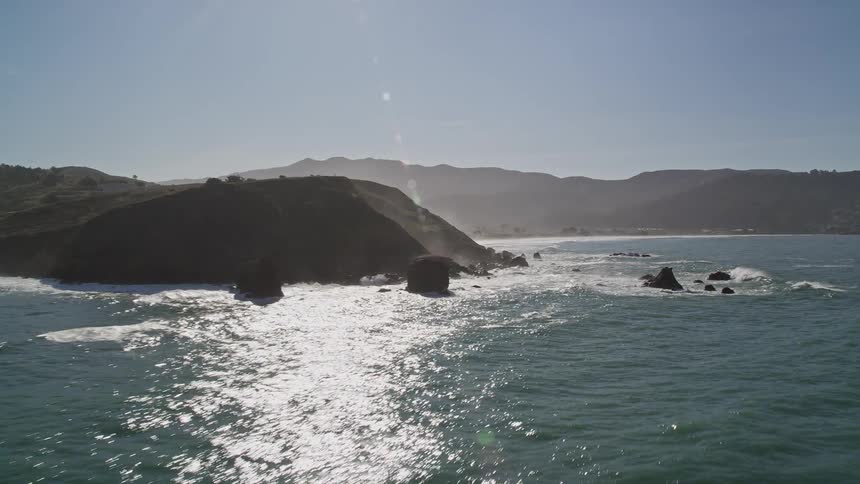 Landscape of rocky mountains by the sea against a cloudless blue sky
