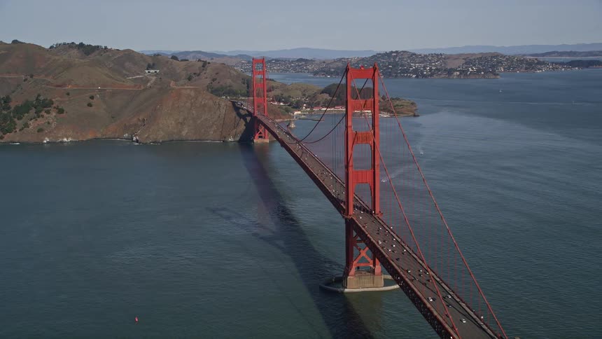 The golden gate bridge painted international orange stretches majestically across the blue waters of the san francisco bay towards the hilly city skyline