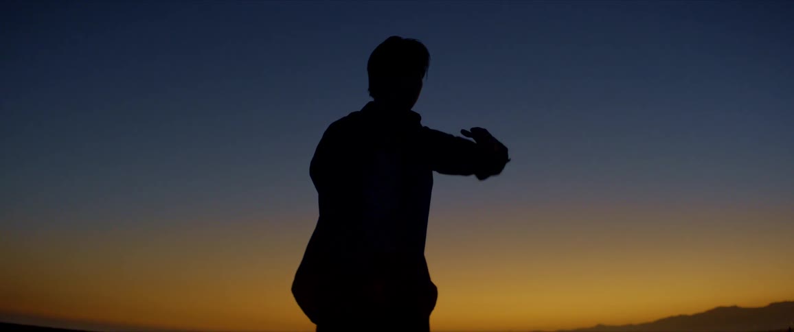 Male dancer is silhouetted against the sunset on the beach