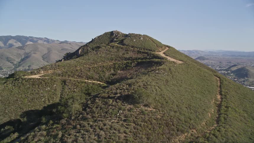 Panorama of a large greenish mountain overlooking an urban city on hills