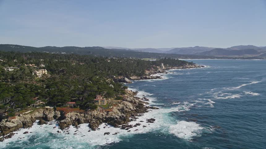 Aerial view of a rugged coastline with waves crashing against the rocks