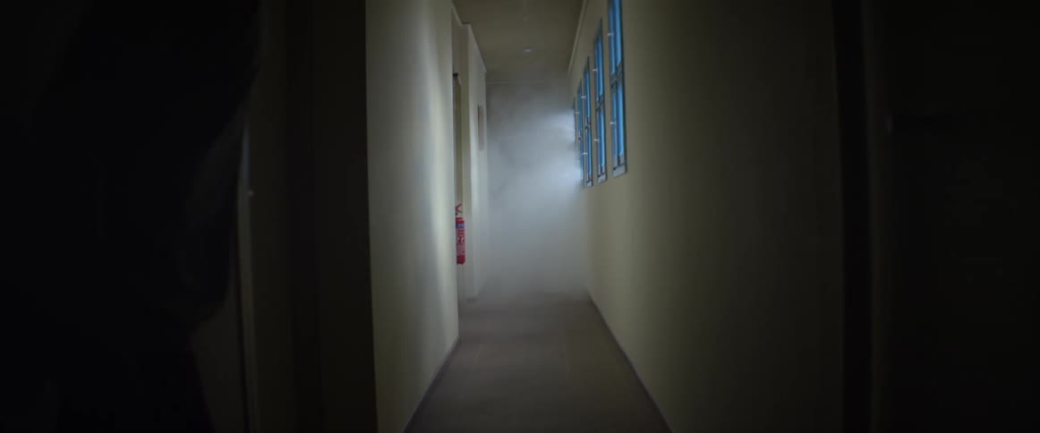 An empty hall with windows giving off light as a man runs down