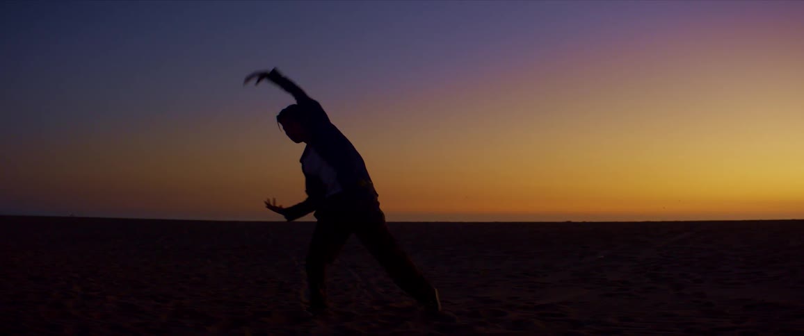 Male partially silhouetted against the red horizon moves through multiple poses while exercising