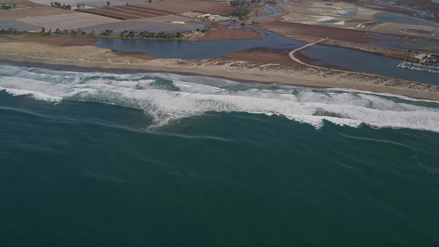 Tidal waves wash ashore on a coast near farms and a marina
