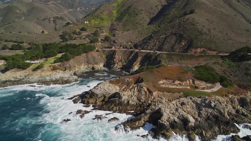 Aerial view of a coast with a road between the sea and the mountains