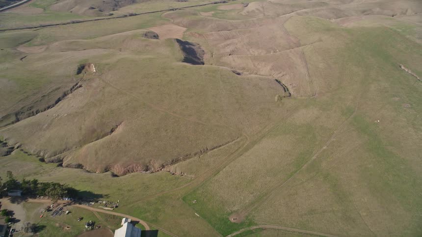 Aerial view of an isolated house in greenish hills and mountains