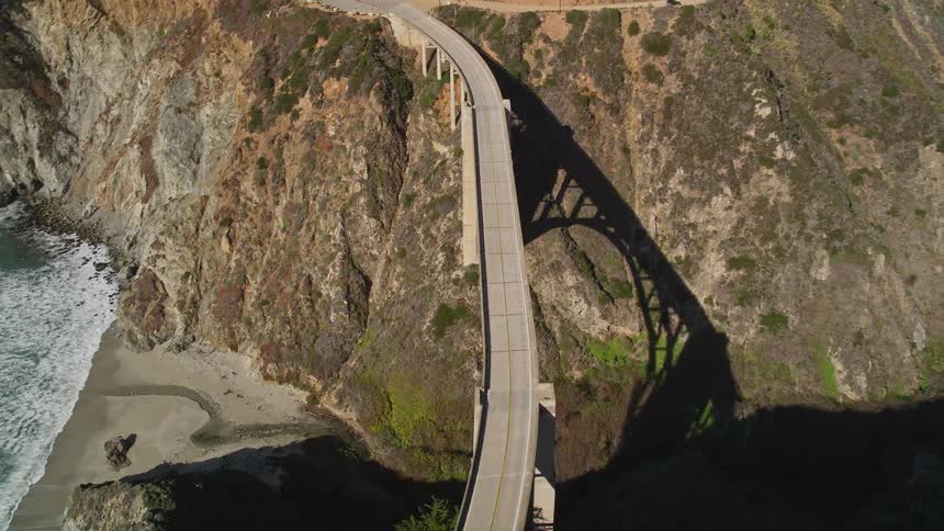 Aerial landscape of a bridge connecting mountains and the seaside