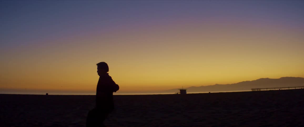 Silhouette of a man dancing on a beach at dusk